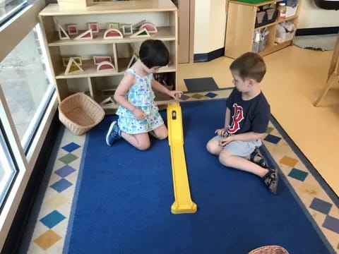 a couple of children playing on a mat in a room with shelves
