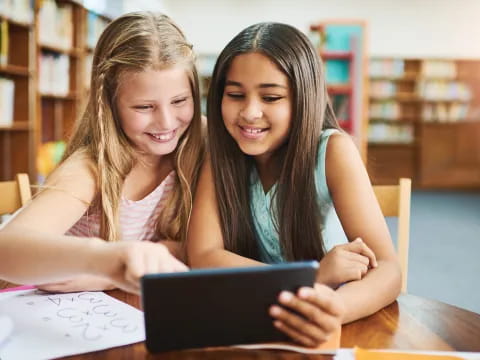 a couple of girls looking at a tablet