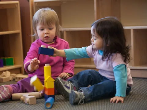 a couple of young girls playing with toys on the floor