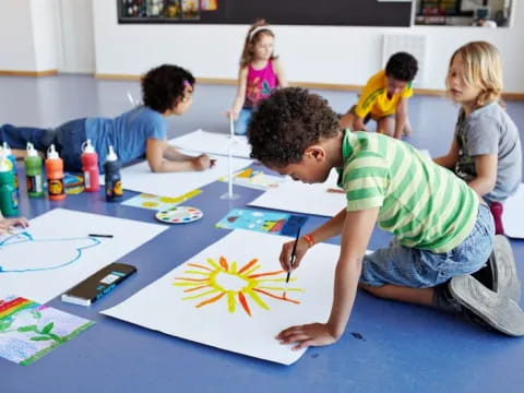 a group of children sitting around a table painting