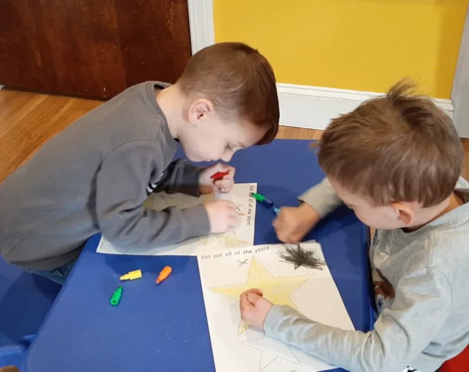 a couple of boys sitting at a table looking at a paper