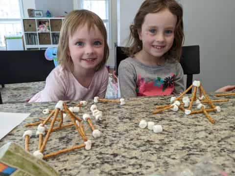 two girls sitting at a table with toys