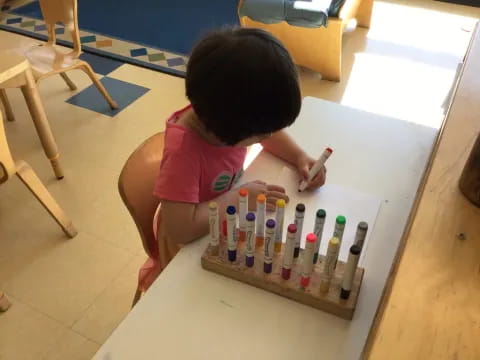 a child sitting at a table with a box of bottles