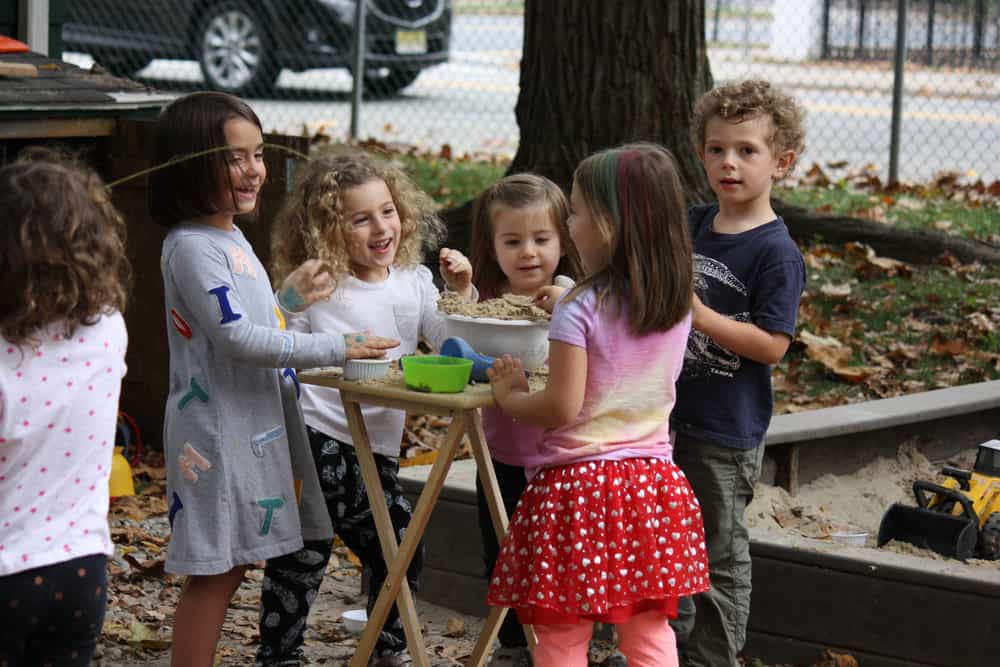 a group of children standing around a table with food