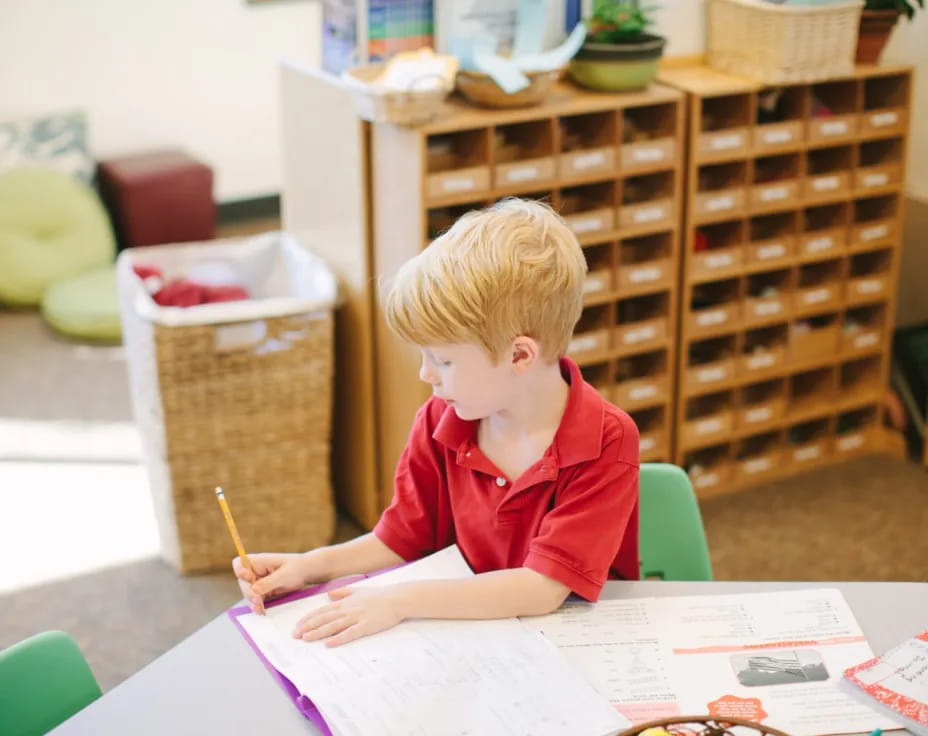 a child sitting at a table writing