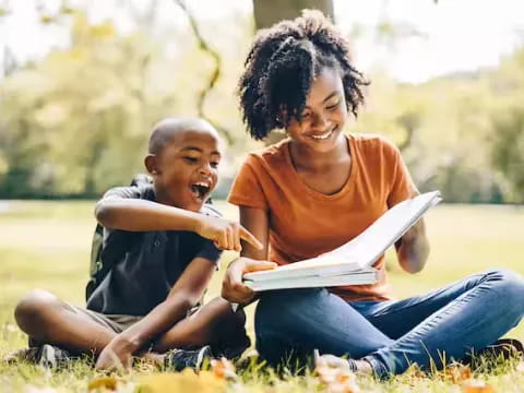 a person and a child reading a book in a grassy field