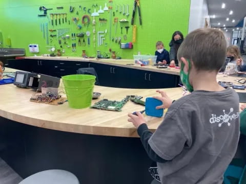 a boy sitting at a table with a blue cup and a green cup