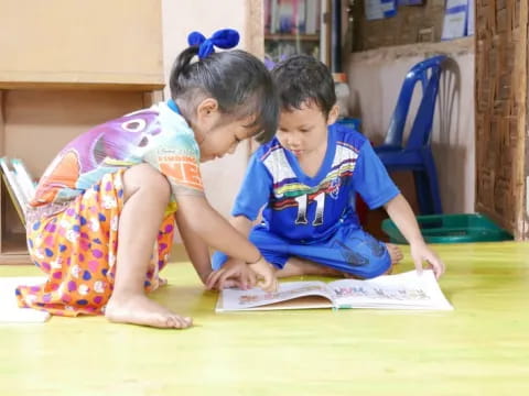 a couple of children sitting at a table looking at a book