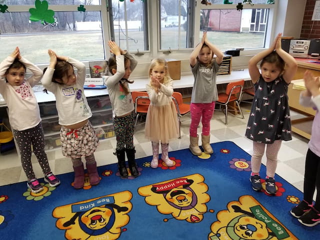 a group of children standing on a mat in a room