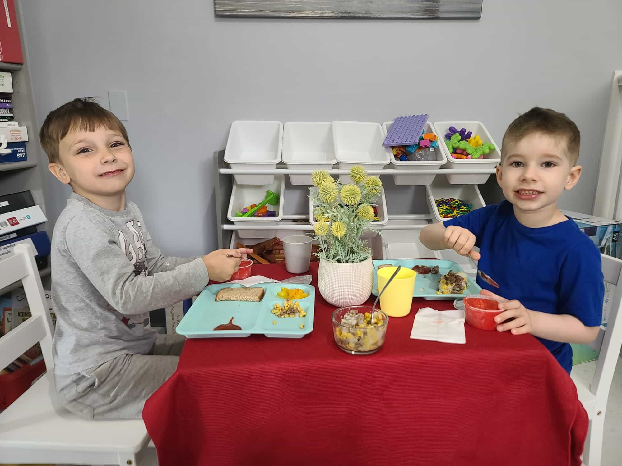 a person and a boy sitting at a table with food and drinks