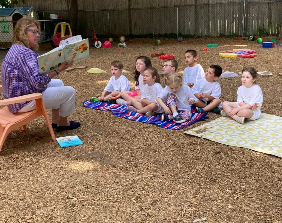 a group of children sitting on a blanket on a blanket in the sand