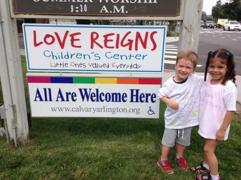 two children standing in front of a sign