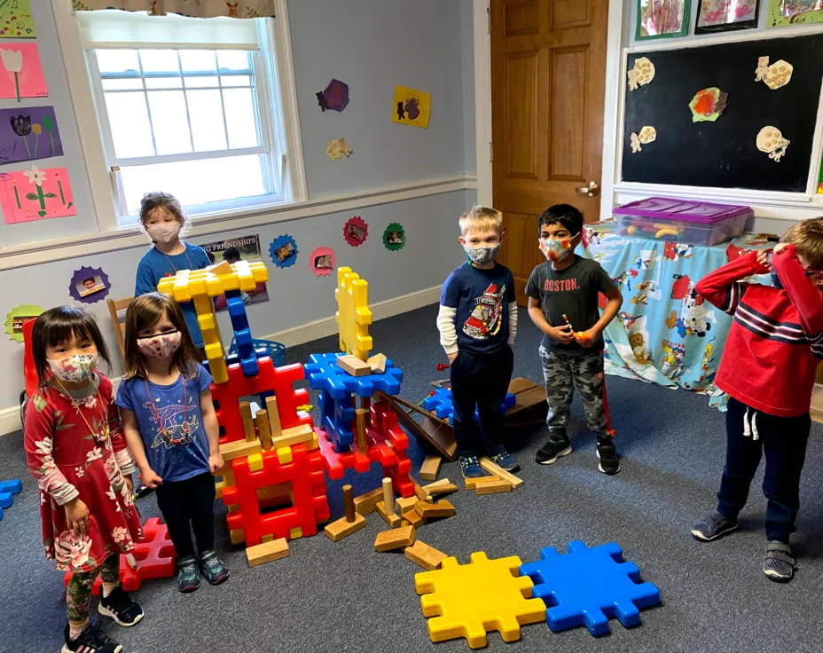 a group of children playing on a blue and yellow toy in a room