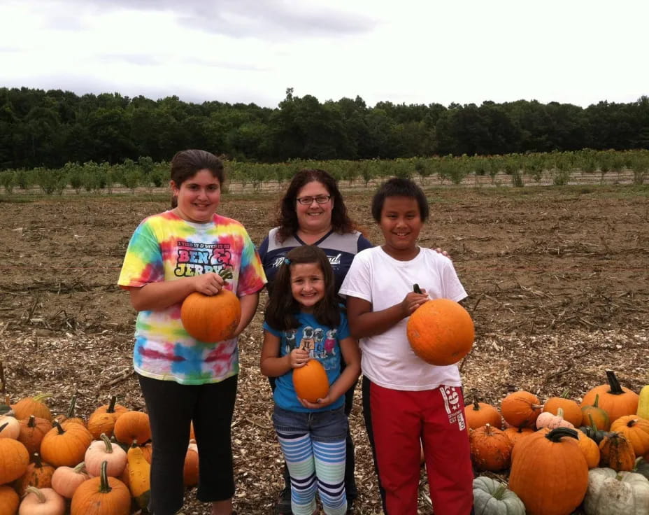 a group of people posing for a photo in front of pumpkins