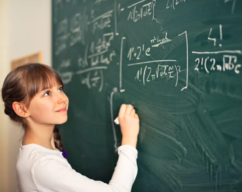 a young girl writing on a chalkboard