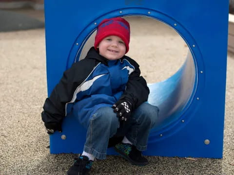 a boy sitting in a blue slide