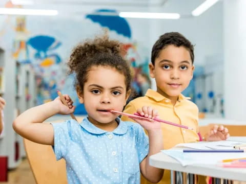 a couple of young children holding pencils