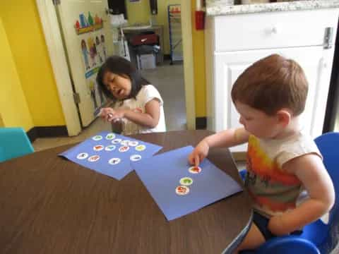 a couple of kids playing with a blue and white puzzle on a table