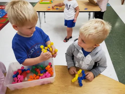 a couple of young boys playing with toys on a table