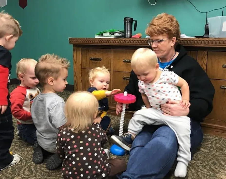 a person sitting in a chair with children around the