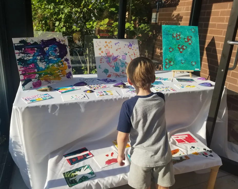 a child standing next to a table with art on it