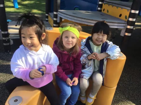 a group of girls sitting on a playground ride