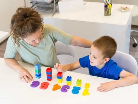 a person and a boy playing with blocks on a table