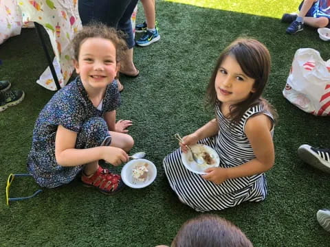 a couple of girls eating on the grass