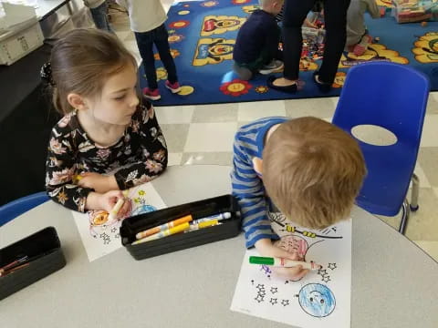 a few children coloring on paper