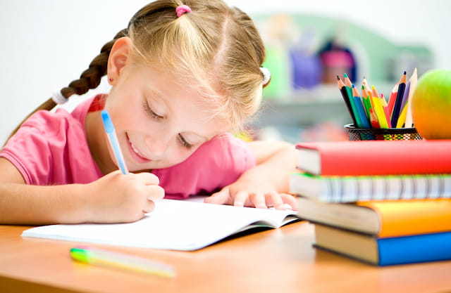 a young girl writing on a book