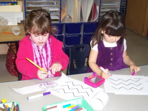 a couple of young girls coloring on paper