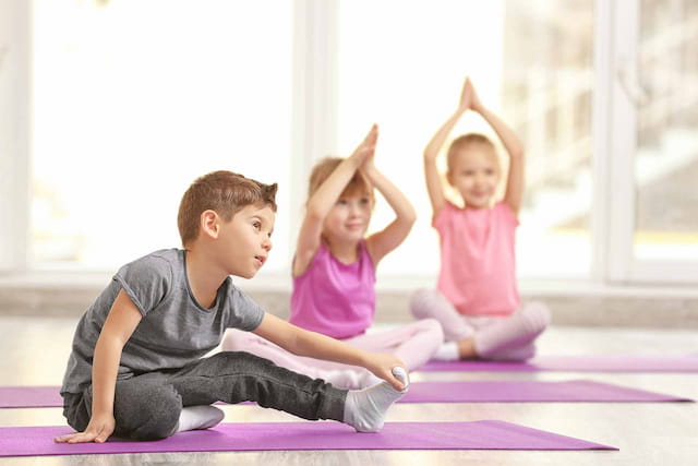 a boy and a girl sitting on a yoga mat