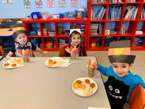 a group of kids sitting at a table with food and drinks