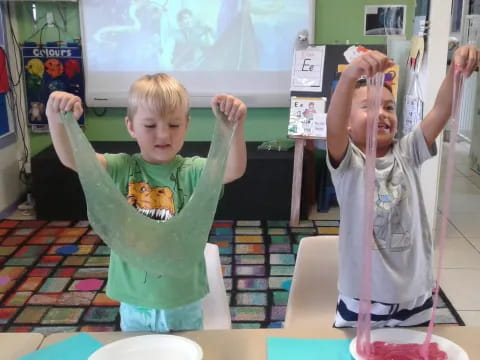 a couple of kids holding their hands up in a classroom