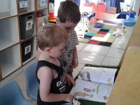 a person and a child looking at a book on a table