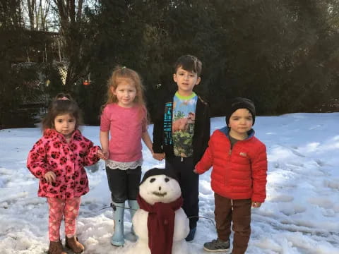 a group of children standing in the snow with a stuffed animal