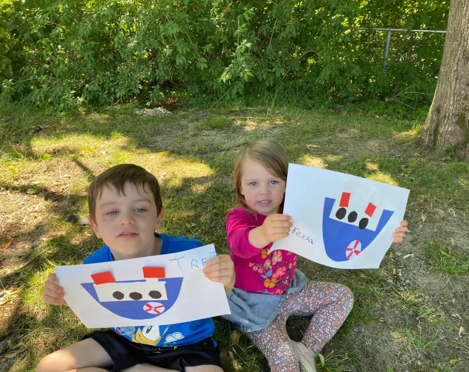 a couple of kids sitting on the ground holding a kite