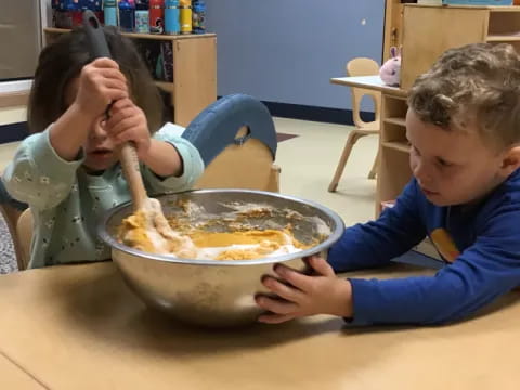 a couple of kids eating from a bowl
