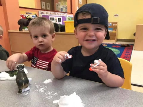 a couple of boys sitting at a table with toys