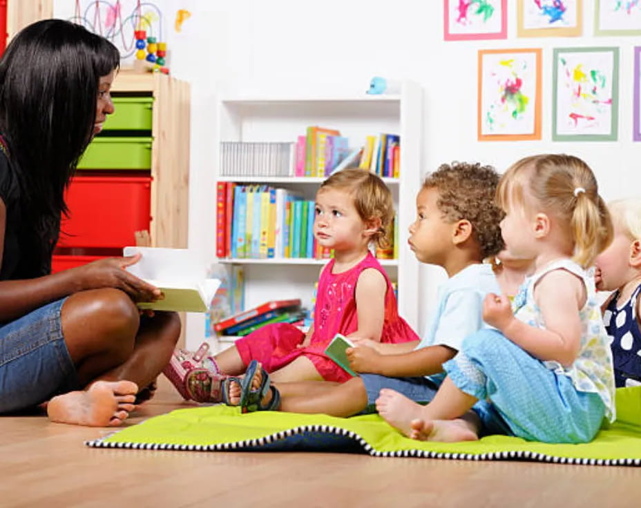 a woman reading a book to a group of children