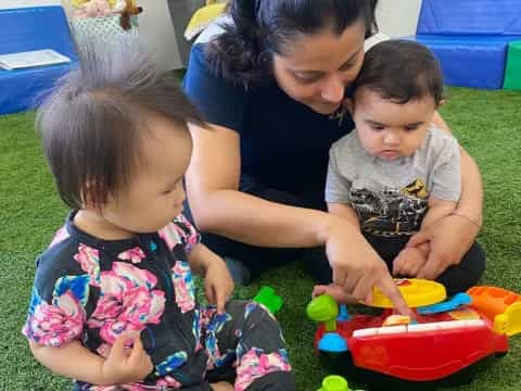 a person and two children playing with toys on the floor