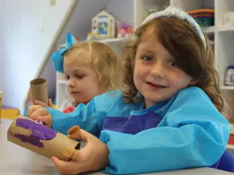 a couple of children playing with a purple toy