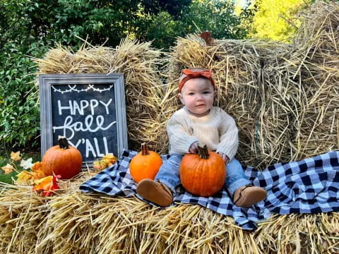 a child sitting on a blanket with pumpkins in front of them