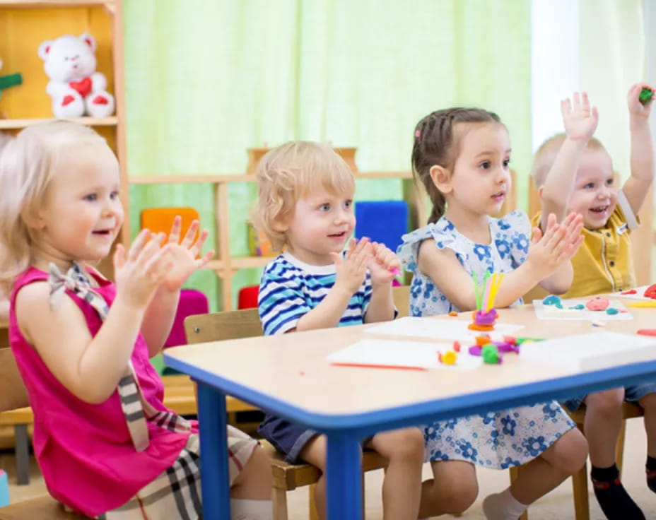 a group of children sitting at a table with a cake