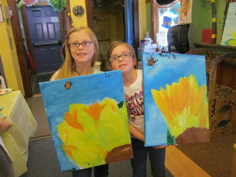 two girls holding colorful paintings