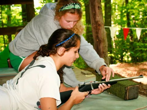 a couple of girls looking at a rifle
