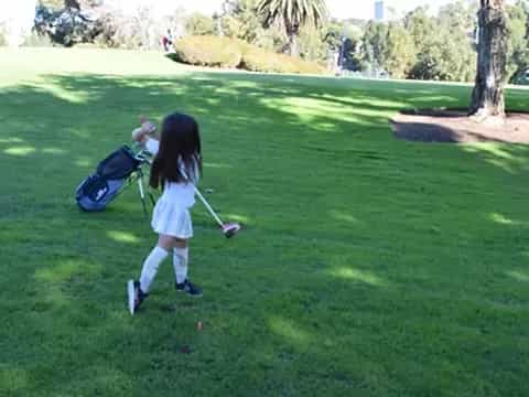 a girl swinging a golf club