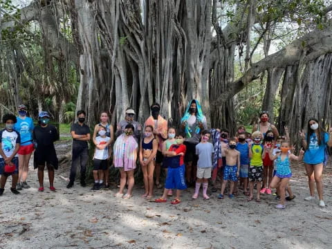 a group of people standing in front of a tree