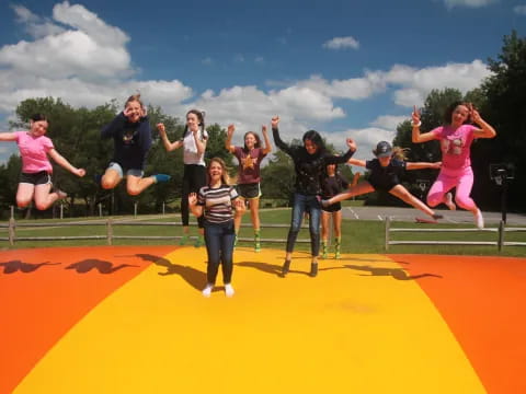 a group of people jumping on an orange and yellow mat
