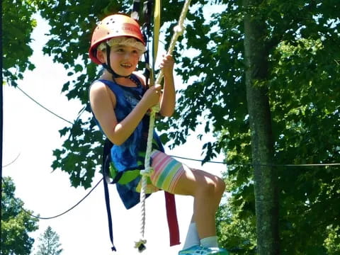 a young boy wearing a helmet and harness on a zip line
